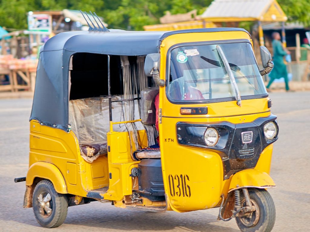 Vibrant yellow auto rickshaw cruising through an urban setting. Perfect for transportation themes.