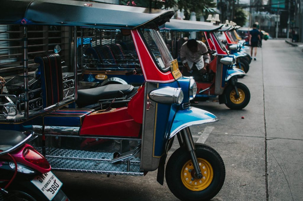 Home Colorful tuk tuks parked in a row on an urban street, emphasizing transportation culture.